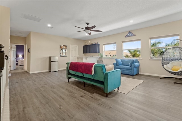 living room featuring baseboards, light wood finished floors, and a healthy amount of sunlight