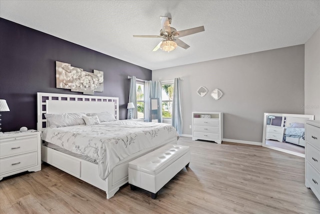 bedroom with light wood-style floors, ceiling fan, a textured ceiling, and baseboards