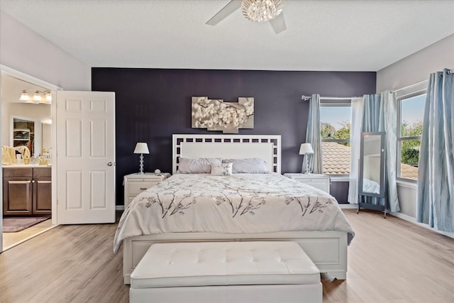 bedroom with light wood-style flooring, an accent wall, baseboards, and ceiling fan