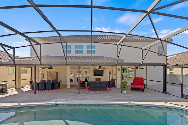 back of property with glass enclosure, a patio area, an outdoor pool, and an outdoor hangout area