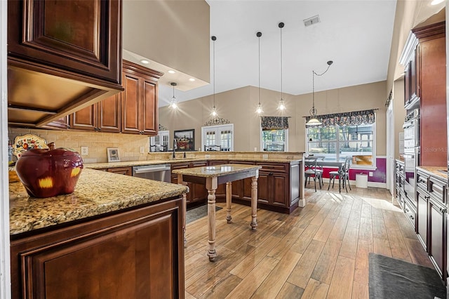 kitchen featuring tasteful backsplash, visible vents, hanging light fixtures, light wood-type flooring, and a peninsula