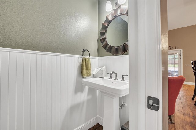 bathroom with a sink, wood finished floors, and wainscoting