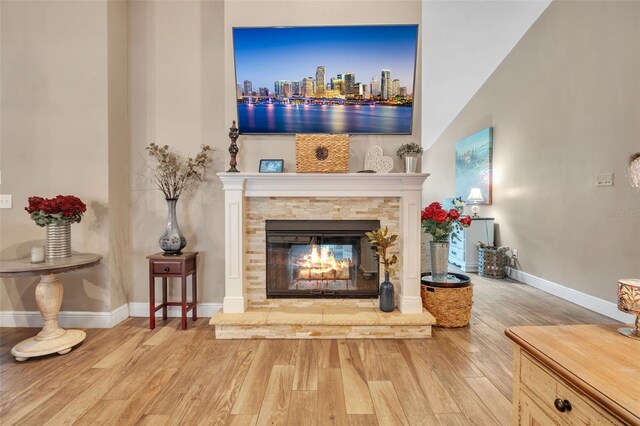 unfurnished room featuring a stone fireplace, wood finished floors, and baseboards