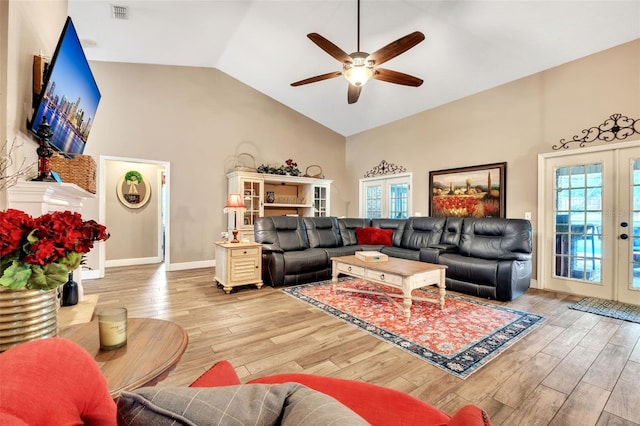 living area with light wood finished floors, visible vents, high vaulted ceiling, and french doors