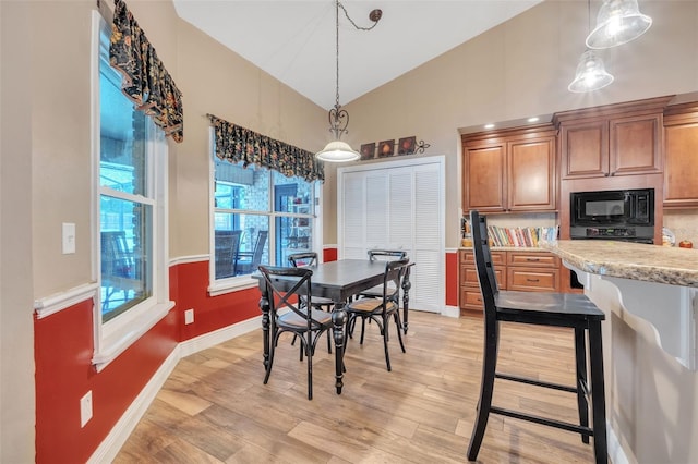 dining space featuring light wood-style floors, high vaulted ceiling, and baseboards