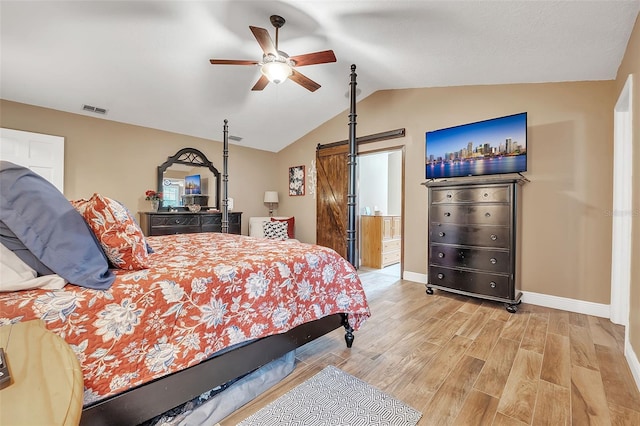 bedroom featuring a barn door, visible vents, baseboards, lofted ceiling, and light wood-style floors