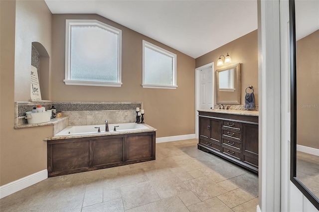 full bathroom with vaulted ceiling, vanity, baseboards, and a bath