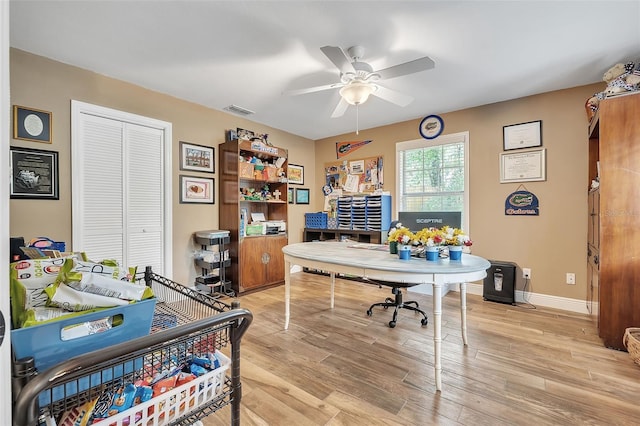 office space with light wood-style floors, baseboards, visible vents, and ceiling fan