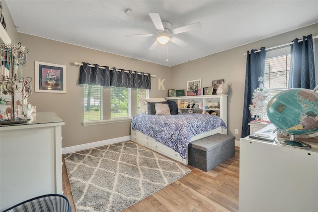 bedroom featuring multiple windows, ceiling fan, baseboards, and wood finished floors