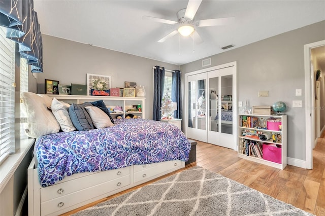 bedroom with french doors, a closet, visible vents, wood finished floors, and baseboards