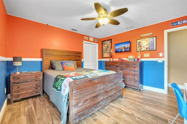 bedroom with a closet, visible vents, a textured ceiling, wood finished floors, and baseboards