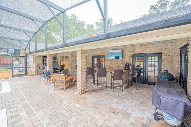 view of patio featuring a lanai, a grill, outdoor dry bar, and french doors