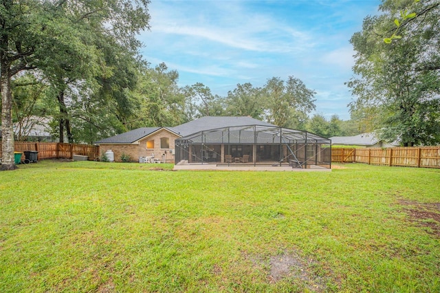 rear view of property featuring glass enclosure, a yard, and a fenced backyard