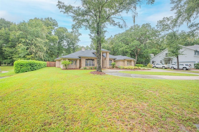 view of front of home with aphalt driveway, a front yard, fence, and a chimney