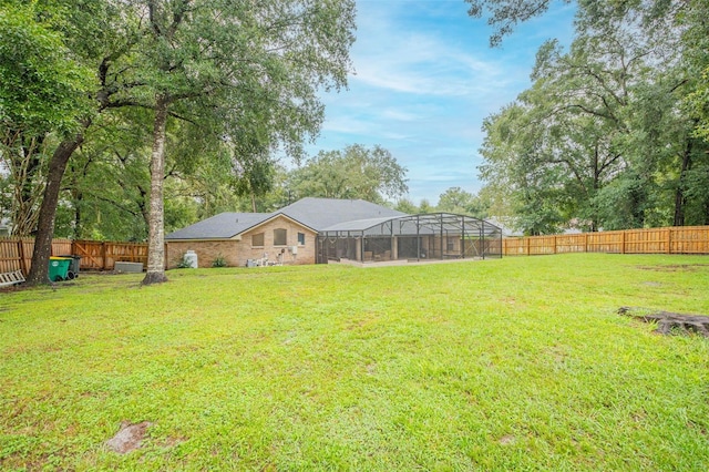 view of yard featuring glass enclosure and a fenced backyard