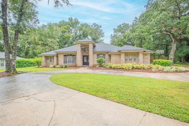 view of front facade with driveway, a front lawn, and brick siding