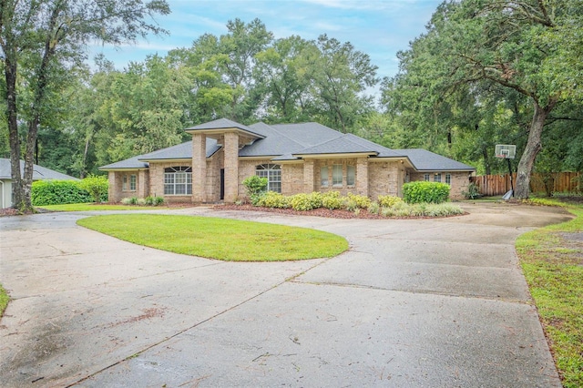 view of front facade featuring fence, curved driveway, and a front lawn