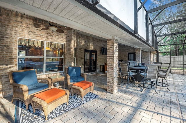 view of patio with a lanai, fence, a ceiling fan, and outdoor dining space