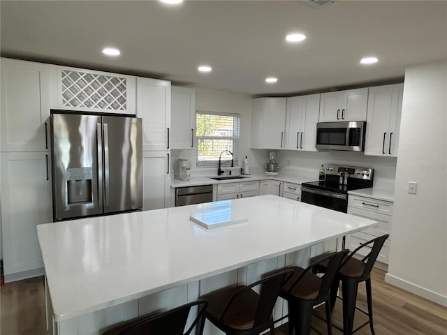 kitchen featuring stainless steel appliances, a sink, a breakfast bar area, and wood finished floors