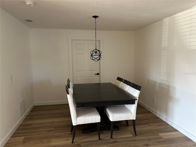 dining area with baseboards, visible vents, and wood finished floors