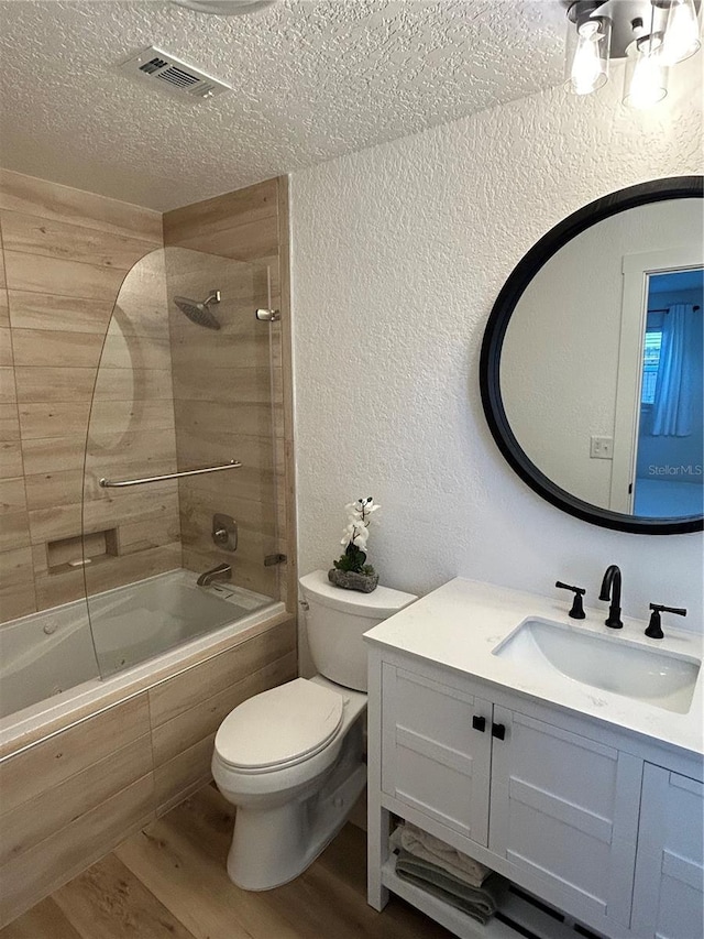 bathroom with visible vents, a textured wall, toilet, wood finished floors, and a textured ceiling