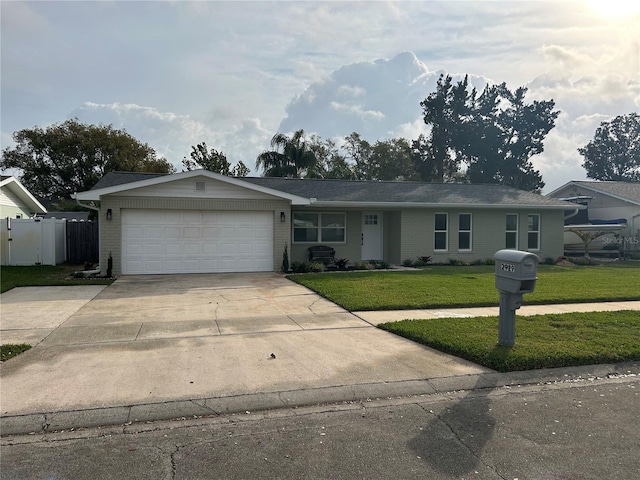 ranch-style house with driveway, a garage, fence, a front yard, and brick siding