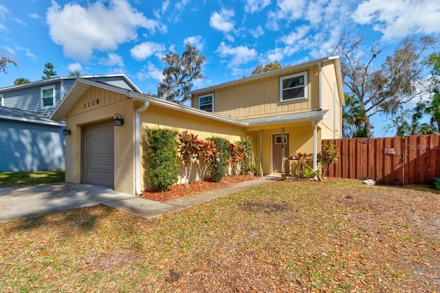 traditional home featuring a garage, driveway, and fence