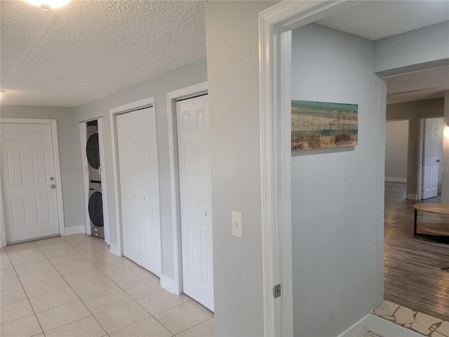 305 Elsie Ave, Daytona Beach, FL 32117 - corridor featuring a textured ceiling, baseboards, stacked washer / dryer, and light tile patterned flooring