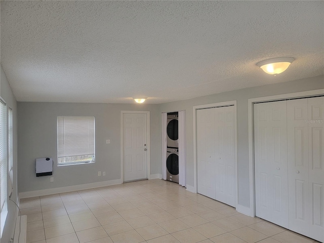 305 Elsie Ave, Daytona Beach, FL 32117 - unfurnished bedroom featuring stacked washer and dryer, multiple windows, heating unit, and two closets