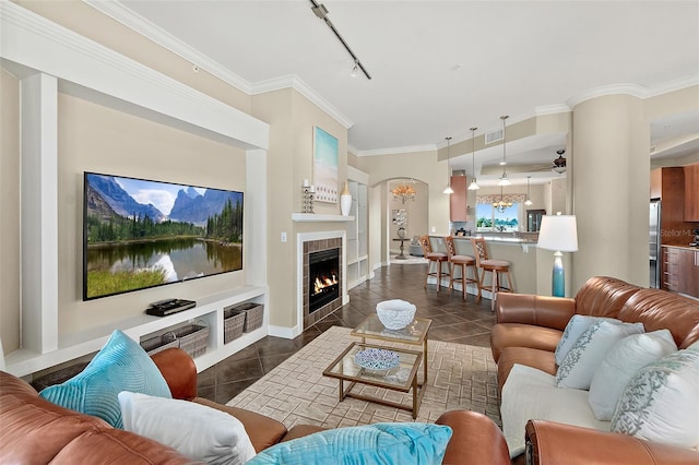 living room with rail lighting, a fireplace, crown molding, and dark tile patterned flooring