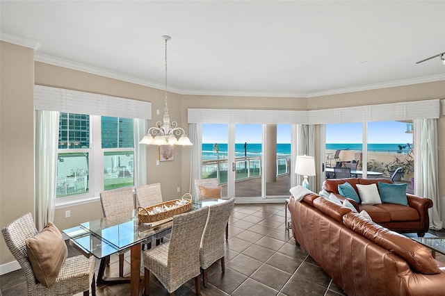 dining space with ornamental molding, dark tile patterned floors, a water view, and an inviting chandelier