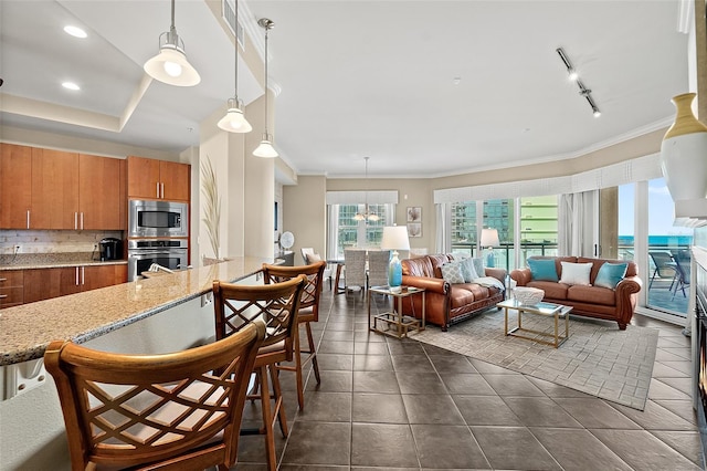 kitchen with stainless steel appliances, backsplash, brown cabinetry, ornamental molding, and a kitchen breakfast bar