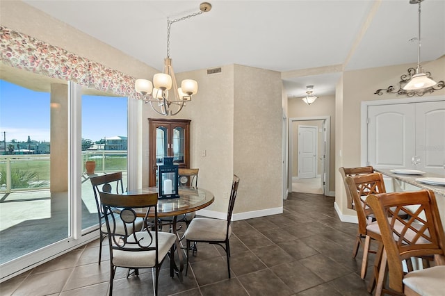 dining area with dark tile patterned flooring, an inviting chandelier, visible vents, and baseboards