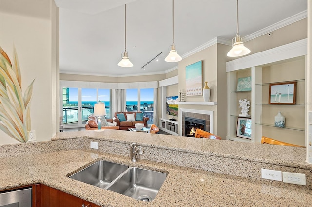 kitchen featuring a tiled fireplace, ornamental molding, open floor plan, light stone countertops, and a sink