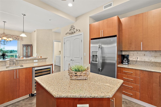 kitchen featuring beverage cooler, a sink, brown cabinetry, stainless steel fridge, and washer / dryer