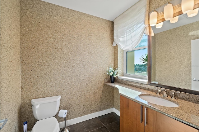 bathroom with tile patterned floors, toilet, vanity, baseboards, and wallpapered walls