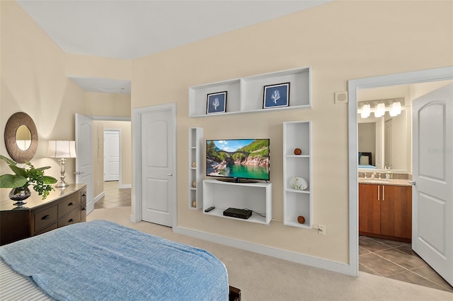 carpeted bedroom featuring a sink, ensuite bath, tile patterned flooring, and baseboards