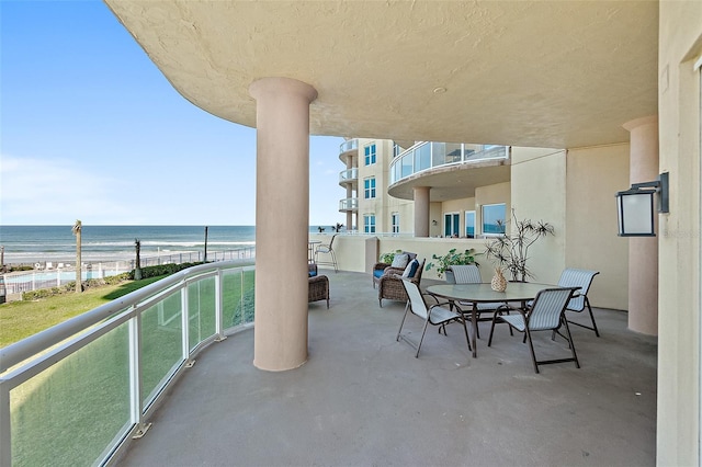 view of patio / terrace featuring a water view, a balcony, and a view of the beach