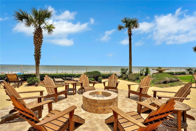 view of patio with an outdoor fire pit, a water view, and fence