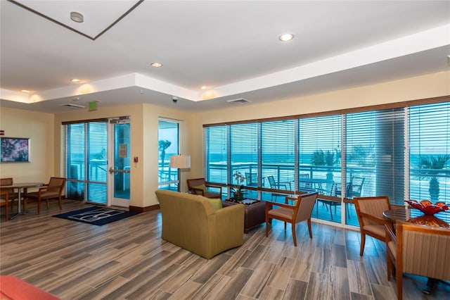 living room featuring wood finished floors, a raised ceiling, visible vents, and recessed lighting