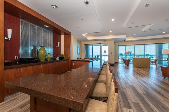 kitchen featuring dark stone countertops, brown cabinets, wood finished floors, and recessed lighting