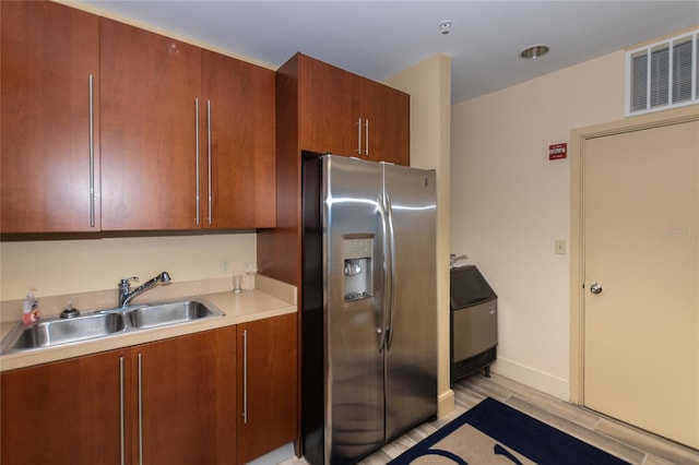 kitchen featuring a sink, visible vents, baseboards, light countertops, and stainless steel fridge