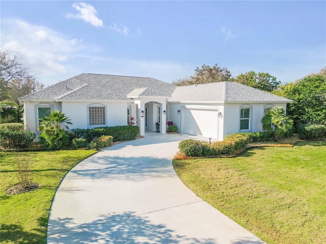 view of front facade featuring a garage, driveway, a front yard, and stucco siding