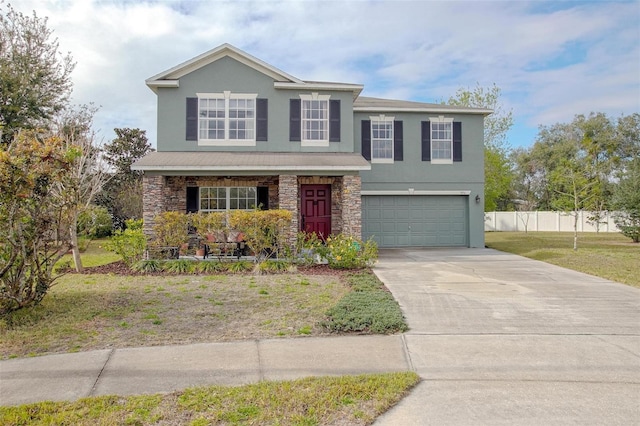 traditional-style home featuring a garage, fence, stone siding, concrete driveway, and stucco siding