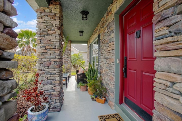 doorway to property featuring stone siding and covered porch