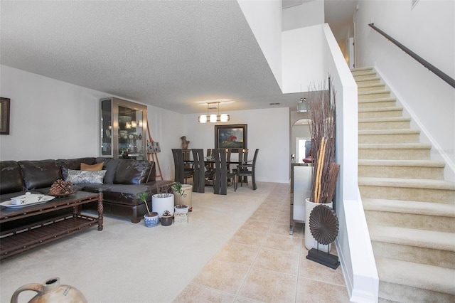 tiled living area with carpet floors, a notable chandelier, a textured ceiling, and stairs