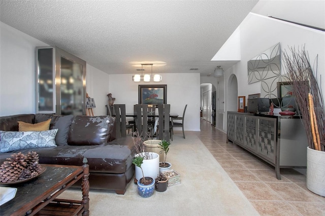 living room with arched walkways, a textured ceiling, and light tile patterned floors