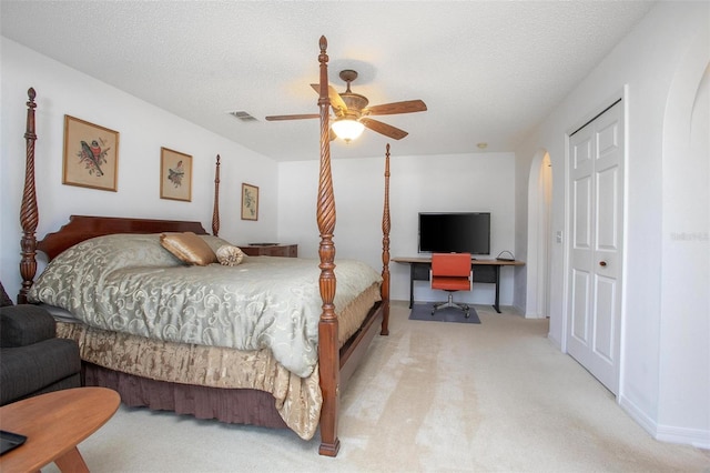 bedroom featuring arched walkways, visible vents, a ceiling fan, carpet flooring, and a textured ceiling