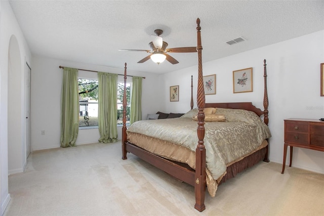 bedroom with carpet, visible vents, ceiling fan, and a textured ceiling