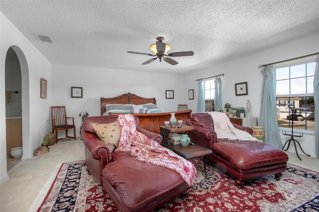 carpeted bedroom featuring visible vents, arched walkways, and a textured ceiling